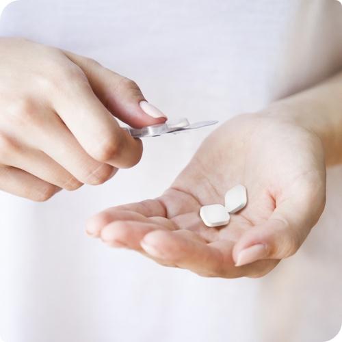 Woman taking indigestion medication - Rennie tablets - out of package.